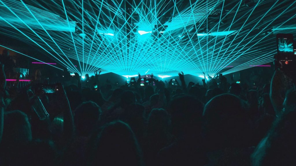 Une scène de boîte de nuit vibrante éclairée par des lumières laser bleues dynamiques, créant une atmosphère électrisante.