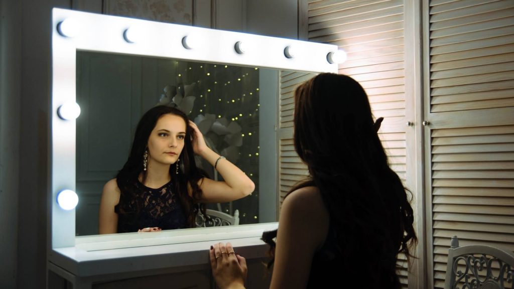 Une jeune fille regardant son reflet dans un miroir, perdue dans son introspection